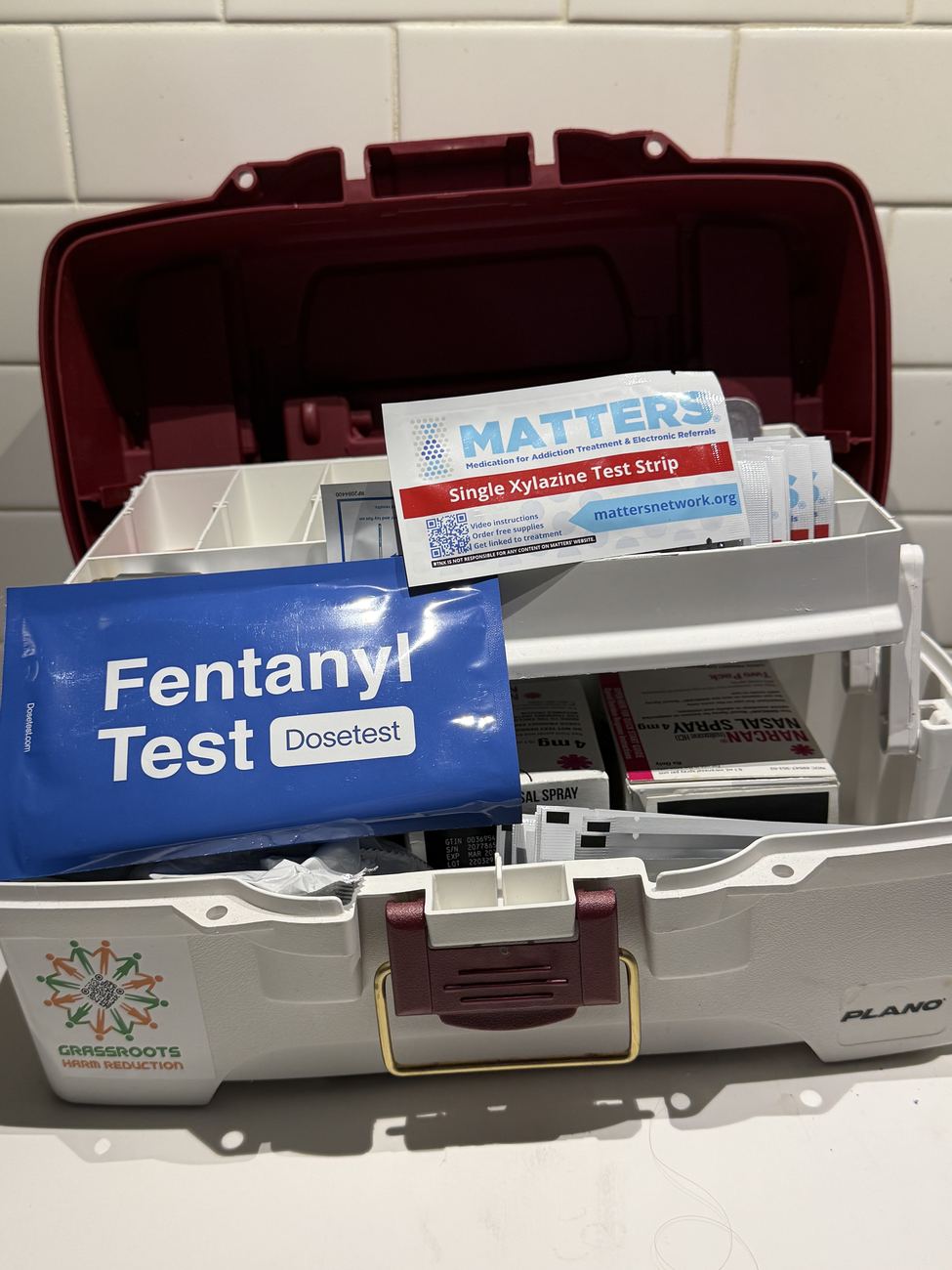 Open field kit containing a DoseTest fentanyl test, a MATTERS xylazine test strip, naloxone nasal spray and a Grassroots Harm Reduction case
