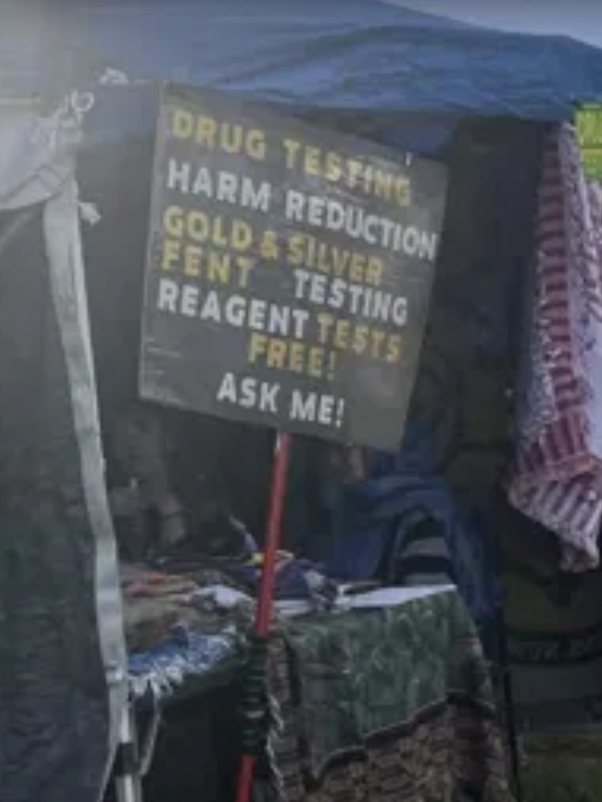 Hand-painted booth sign reading: Drug Testing, Harm Reduction, Gold & Silver, Fent Testing, Reagent Tests Free, Ask Me